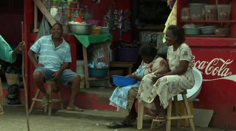 PEOPLE SITTING IN FRONT OF PAKRO STORE OLD WOMAN CROSSES Stock Footage 58057240