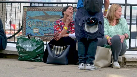 People sitting on The Queen's Walk in The Queue Video stock 215932198