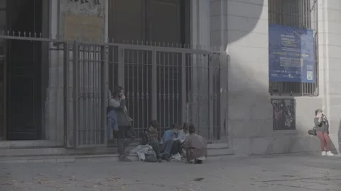 People sitting on the sidewalk along the roadside in Madrid, Spain 動画素材 345029562