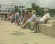 People sitting on stone wall next to sea SD Footage