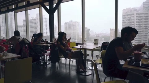 People sitting at tables next to big window with view of Bangkok Stock Footage 81880887