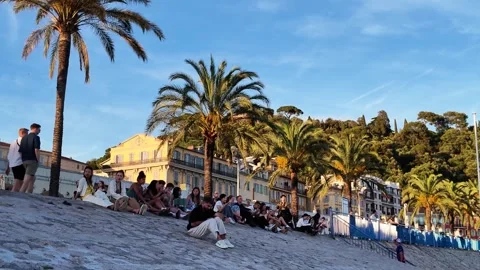 People sitting under palm trees at sunset on promenade Video stock 336922827