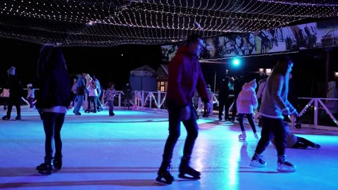 People skate in the winter in the evening under the neon lights on the ice rink Stock Footage 156937547
