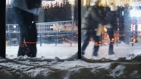 People skating in the winter evening. view through a transparent glass plastic f Stock Footage 327539579