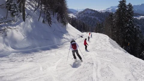 People skiing and snowboarding down snowy mountain slope Stock Footage 342055331