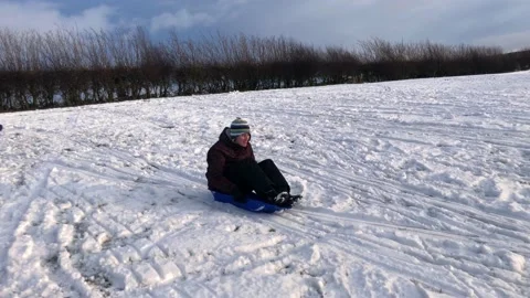 People sledging down a hill on a snowy day Stock Footage 147232382