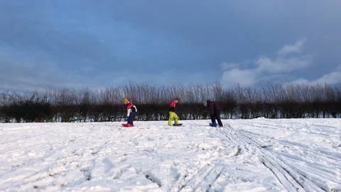 People sledging down a hill on a snowy day Stock Footage 147232676