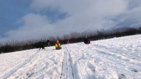 People sledging down a hill on a snowy day Stock Footage 147233132
