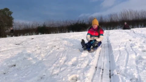 People sledging down a hill on a snowy day Stock Footage 147233190