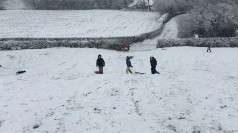 People sledging down a hill on a snowy day Stock Footage 147256398