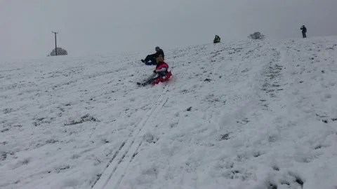 People sledging down a hill on a snowy day Stock Footage 147256471