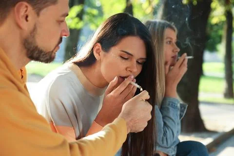 People smoking cigarettes outdoors on sunny day Stock Photos