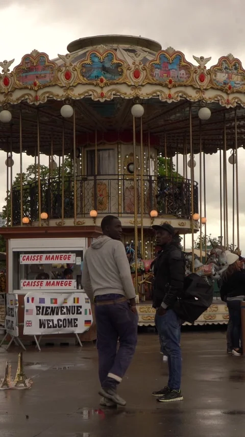 People Socializing in Front of Carousel at Outdoor Fairground on Overcast Day Stock Footage 334940216