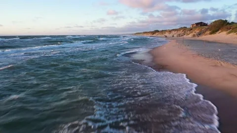 People spend time on empty sea beach near hill with house Stock Footage 148782532