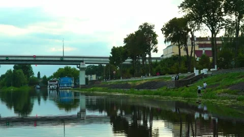 People spend time by the river with trees and buildings in the background during Vídeos de archivo 340447988
