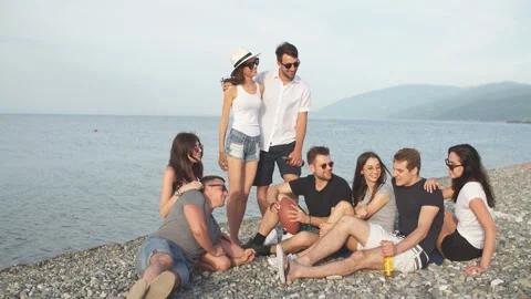 People spending nice time together while sitting on beach, having fun and Stock Footage 100309430
