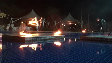 People spin fire chains at night by the fountain in the hotel show Video stock 146936450