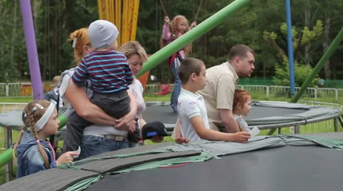 People stand side by side in the park, children jump Vidéo 65396882