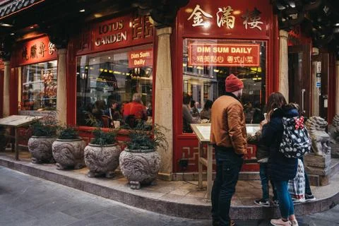 People standing and reading a menu outside a restaurant in Chinatown, London, Stock Photos