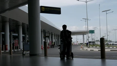 People standing and waiting eith his trolley in drop off area of the airport Stock Footage 122584322