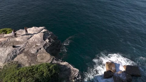 People standing on cliffs looking out to sea from aerial view 스톡 동영상 336999945