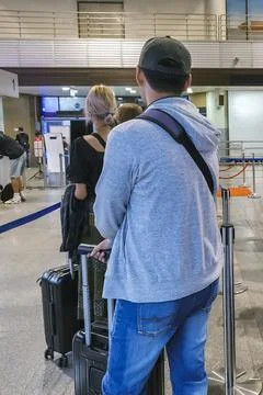 People standing with luggage in queue to check in at airport terminal. Man .. Stock Photos
