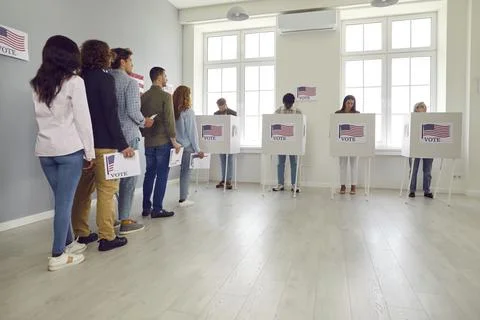 People standing in a queue with ballot paper at polling station at vote center. Stock Photos