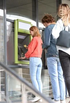People standing in queue to cash machine outdoors Stock Photos