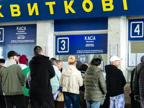 People standing in a queue at a railway ticket office window, waiting patiently Stock Photos