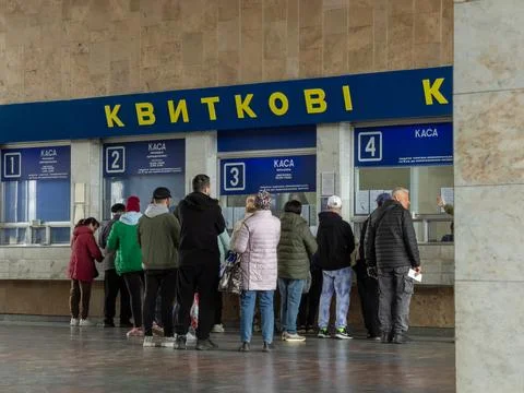 People standing in a queue at the ticket office of a busy railway station to Stock Photos