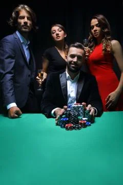 People standing at the table, looking, while a person is betting Stock Photos
