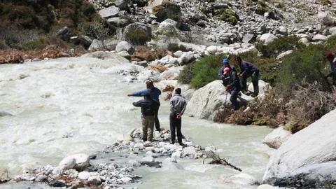 People at the stream throwing a rope beyond the water stream Stock Footage 77450089