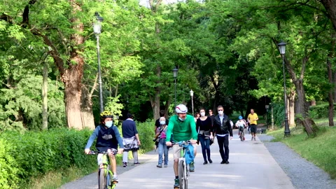 People stroll, run and ride bicycles in the public park. Stock Footage 130275407