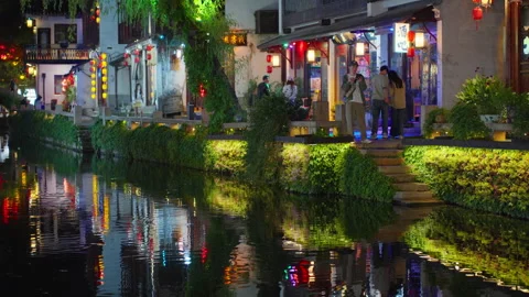 People Strolling by Illuminated Canal-Side Shops at Night in Zhouzhuang, China Stock Footage 337266322