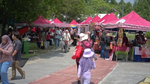 People strolling past rows of red canopy stalls at an outdoor festival Stock Footage 346350183