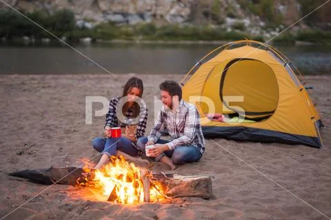 People, summer tourism and nature concept - couple near camp fire warming up Stock Photos