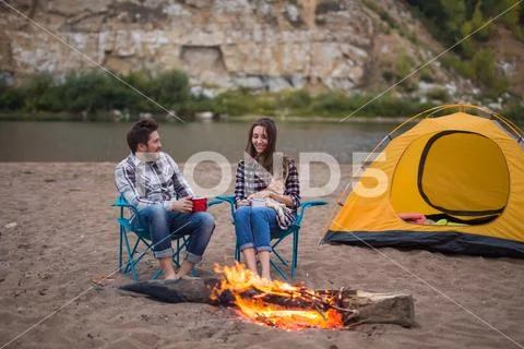 People, summer tourism and nature concept - couple near camp fire warming up Stock Photos