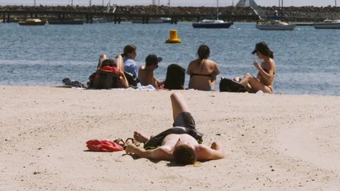 People sunbathing in a beach, water background Stock Footage 82375649