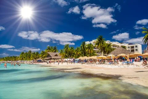 People sunbathing on the white sand beach with umbrellas, bungalow bar and co Stock Photos