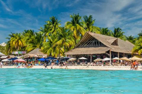 People sunbathing on the white sand beach with umbrellas, bungalow bar and co Stock Photos