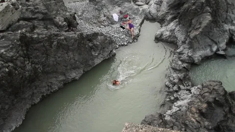 People swim in the lake formed by solidified volcanic lava. Mountain landscape. Video stock 119995853