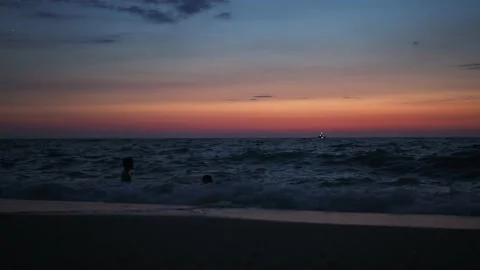 People swim in the sea at dusk after sunset. in the distance, children can be Stock Footage 166314377
