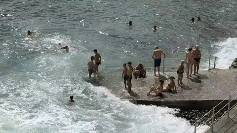 People swimming in Atlantic waves at the beach in Funchal, Madeira, Portugal, on Stock Footage 346247205