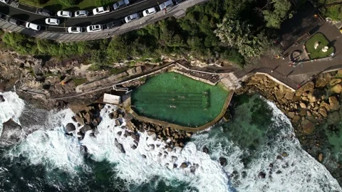 People swimming in Bronte Baths ocean pool with waves crashing. Zoom out Stock Footage 168914592