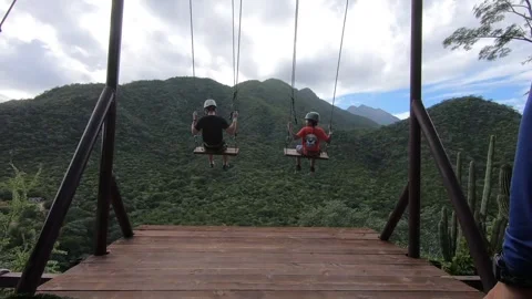 People swinging on swing looking over mountain Stock Footage 248477310