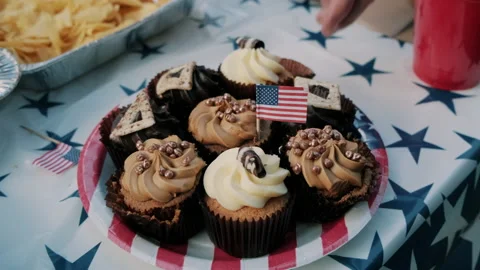 People taking cupcakes with a tiny USA flag in the middle at 4th of July Party Stock Footage 133616910