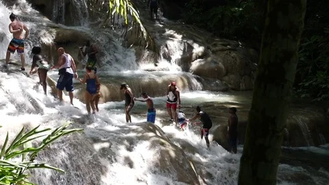 PEOPLE TAKING BY THE HAND CLIMBING RIVER FALLS IN OCHO RIOS JAMAICA Stock Footage 85385212