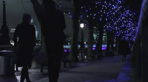 People taking a night time walk on a path by the River Thames Stock Footage 44763902