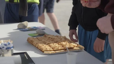 People Taking Pastries from Outdoor Table at Casual Gathering in Daylight 動画素材 347124355