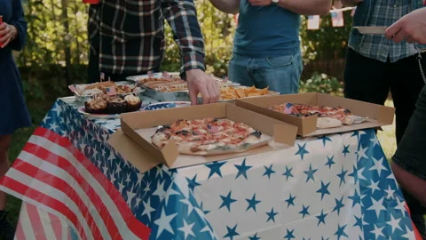 People taking plates from table full of food at 4th of July outdoors Party Stock Footage 133617744